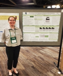 Alum Paige Baisley standing in front of a poster