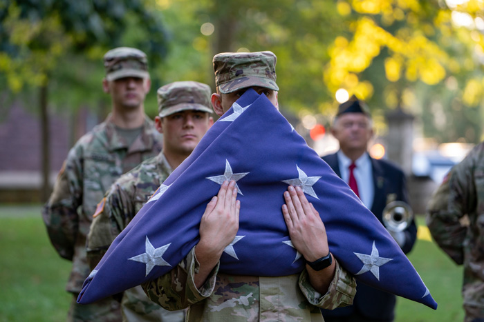 an ROTC cadet holds a folded flag 