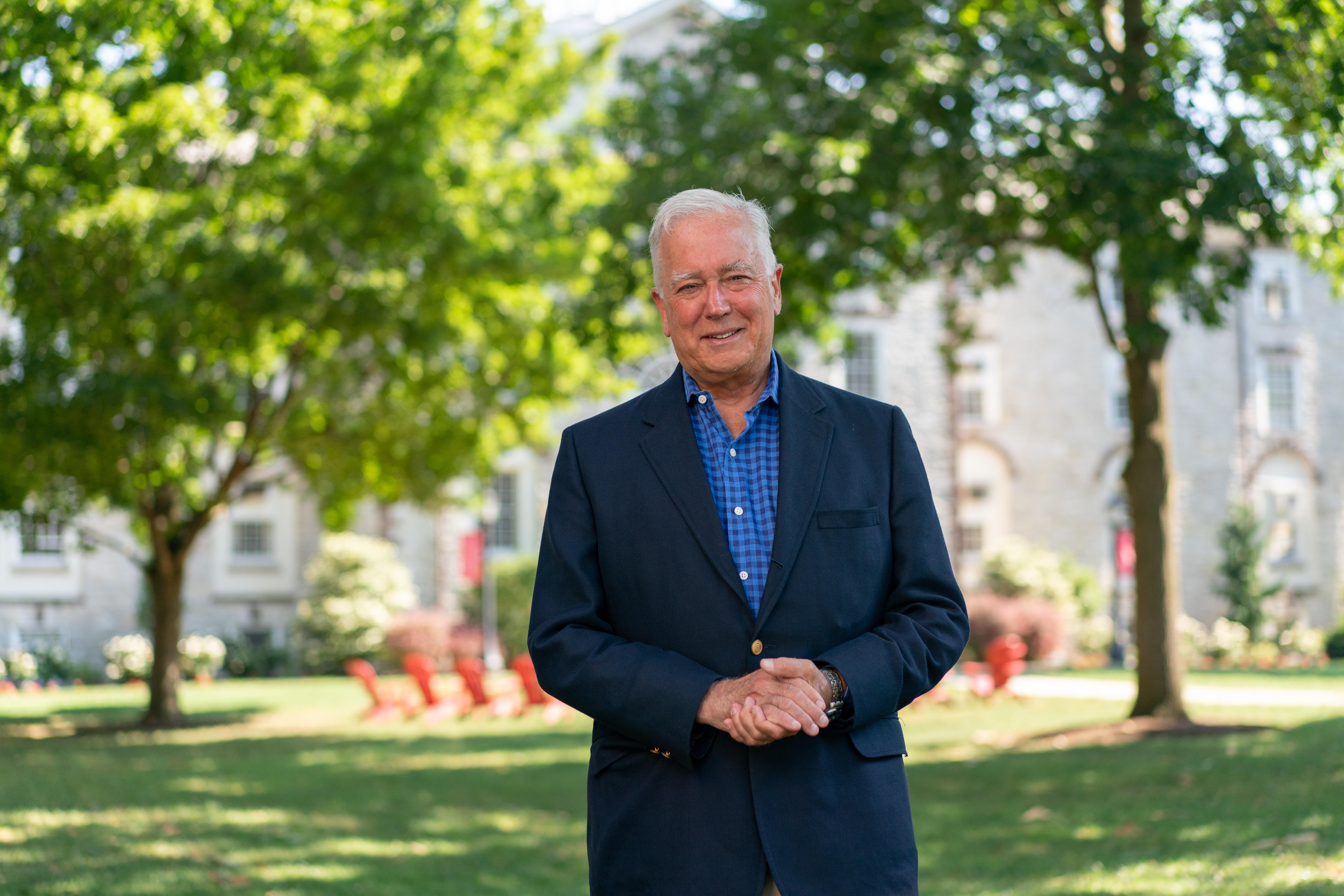 Photo of Dickinson College President John E. Jones III standing in a green lawn in front of a limestone building.