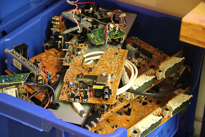 The internal electronics and small motors of toys are stacked in a blue bin at the Makery.