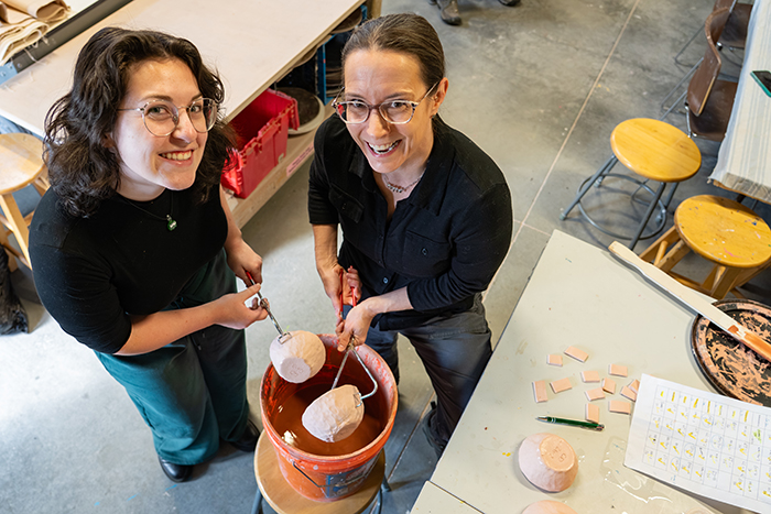 Two women hold a drinking vessel in the studios of the Carlisle Arts Learning Center.