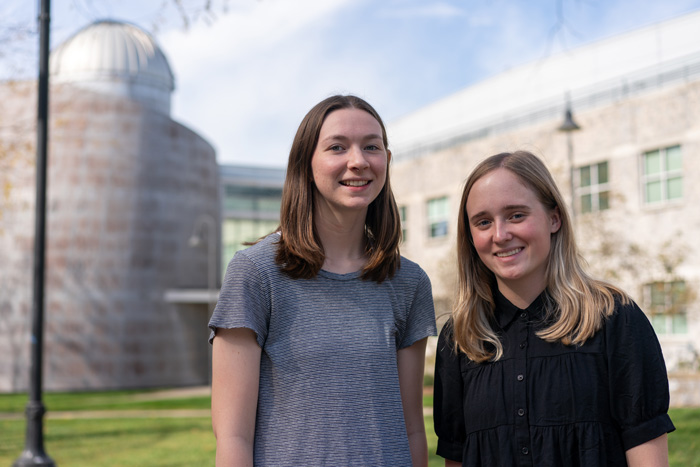 two students pose outside an academic building