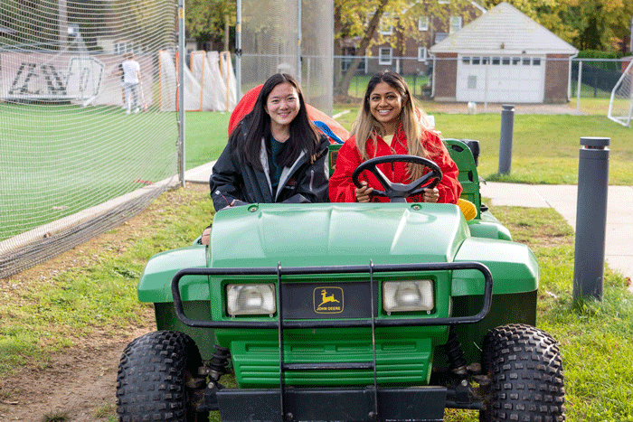 students drive a cart full of sports equipment