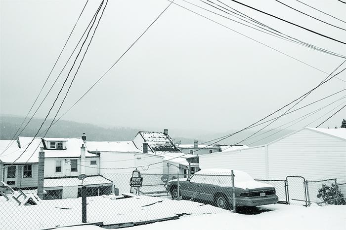 Photograph of a snow scene with a house and a car in the driveway.