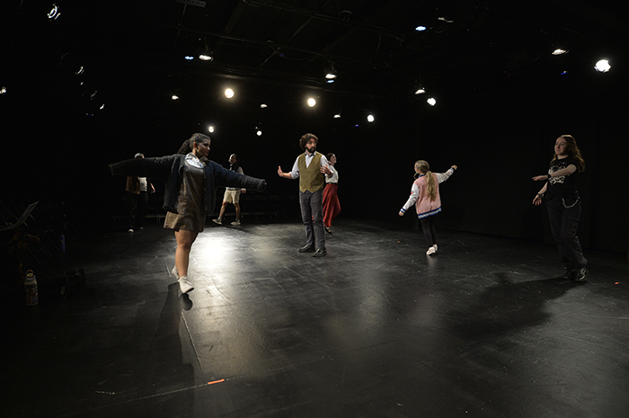 Students onstage, with bright lights above them.