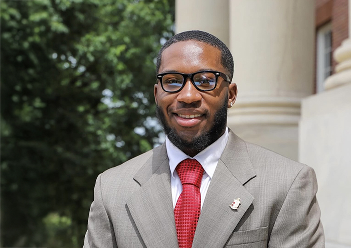a young man in a tan suit, white shirt and red tie