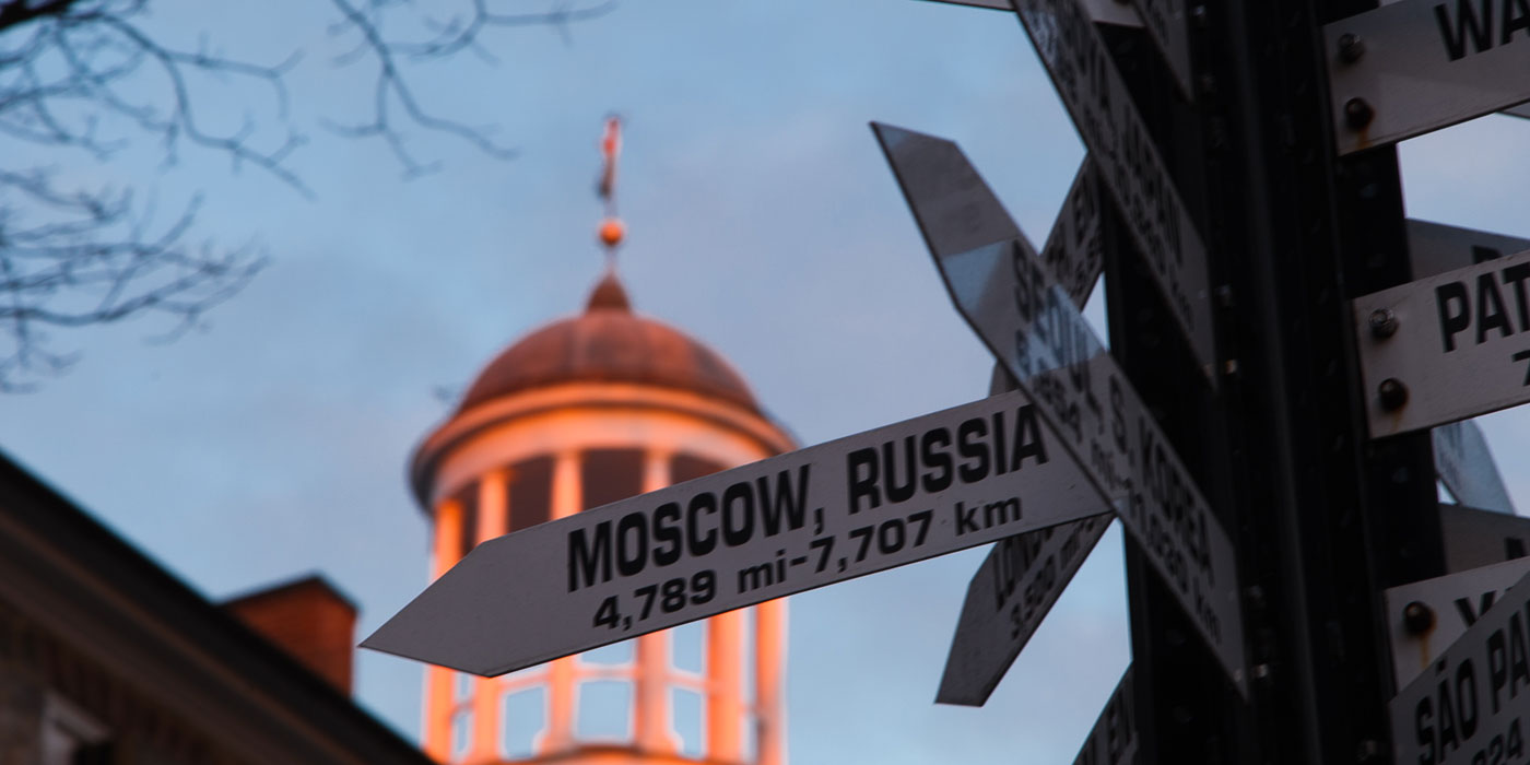 A photograph of Dickinson's global directional sign in the foreground and the top of the Old West building in the background.