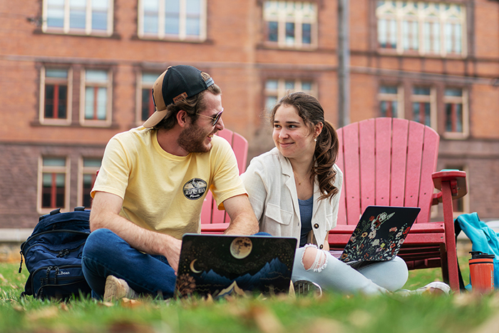 Two students use their laptops outside on the grass at Dickinson College