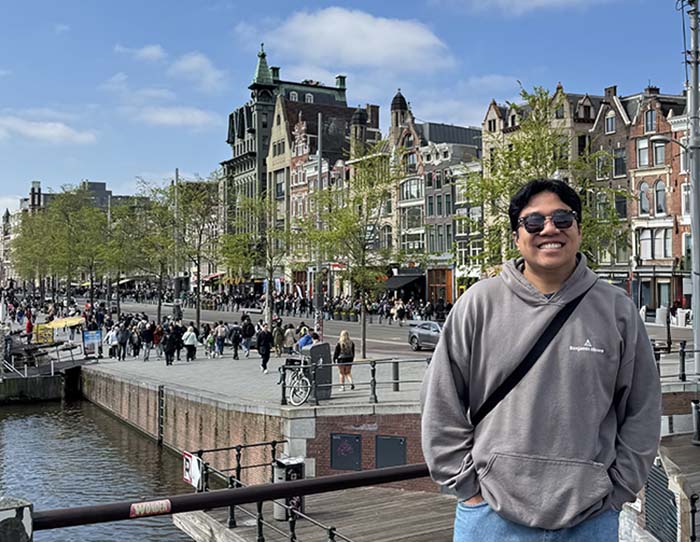 a student wearing sunglasses at a waterfront.