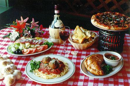 A dinner table full with an assortment of traditional Italian dishes including bread, pizza, and pasta.