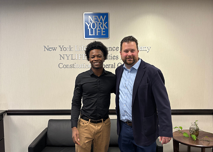 A recent graduate and an alum stand together in a Met Life office.