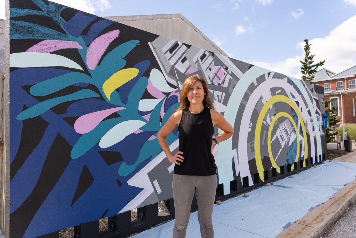 Visiting Artist Joelle Dietrick poses by her new mural at the Goodyear Gallery. Photo by Dan Loh.