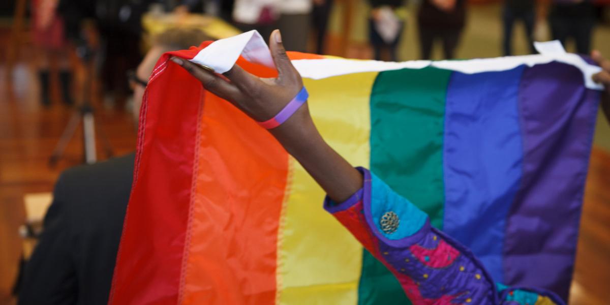 Hands holding a rainbow flag.