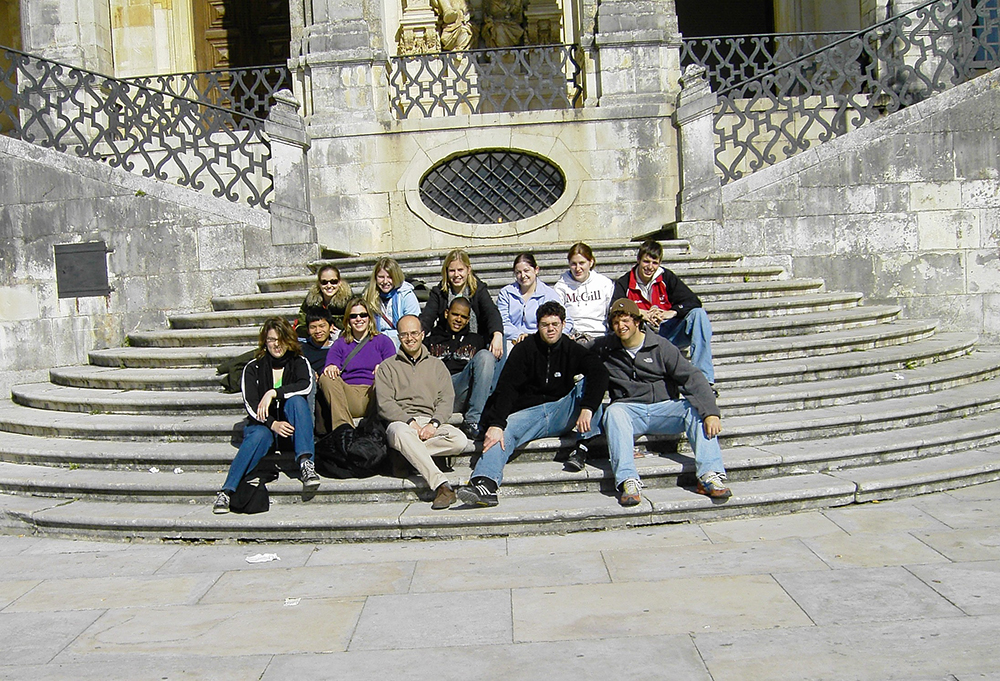 Malaga Director Marcelo Borges takes a photo with students on a set of outdoor stone steps in Spring 2006