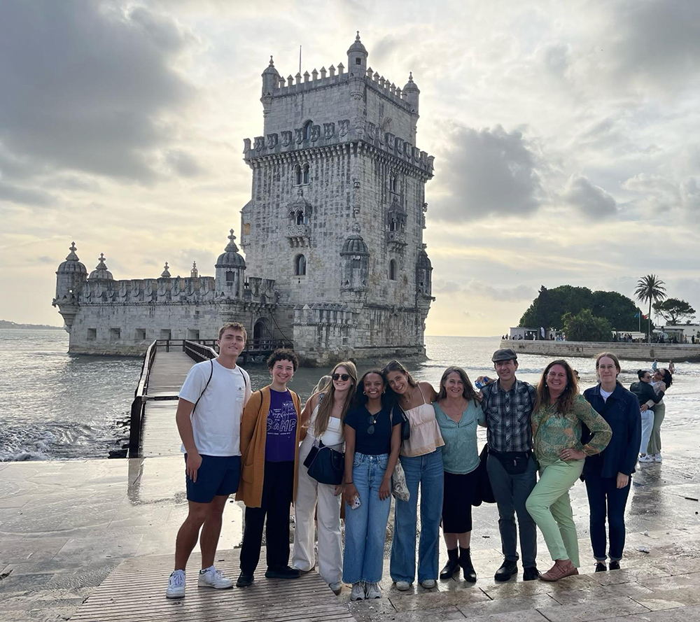 Malaga Program Direcor Margaret Frohlich poses with students for a sea-side photo in Spain