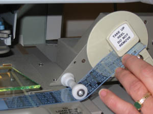 hands feeding microfilm beneath reader glass