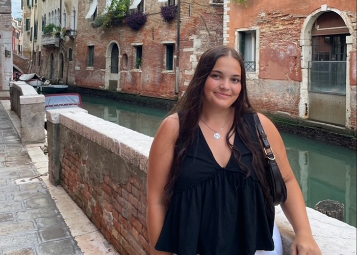 young woman poses by a fence