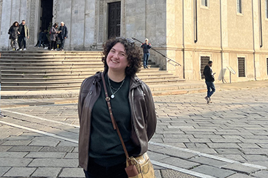 Young person in Bologna, smiling and posing in front of a historic building.