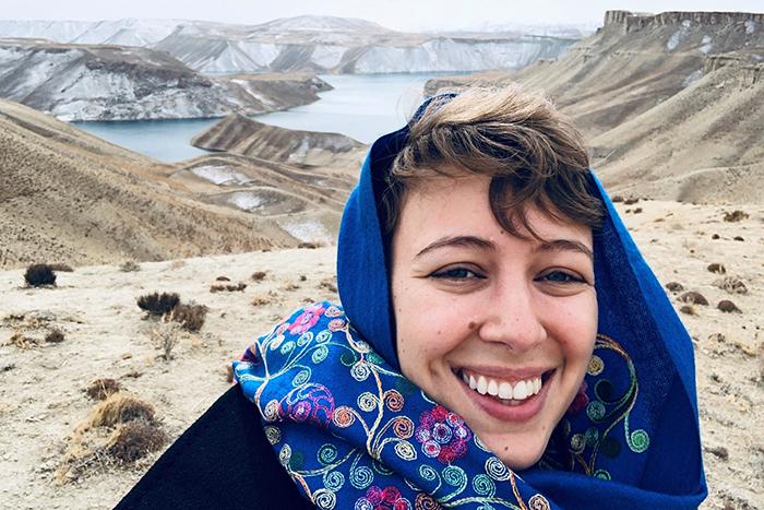 Photo of Siobhán O’Grady standing in front of mountainous terrain in Afghanistan.