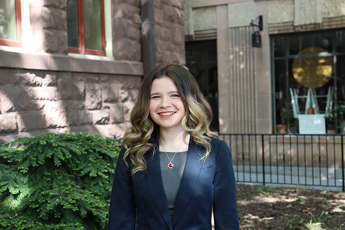 a girl poses in front of a limestone building on Dickinson's campus