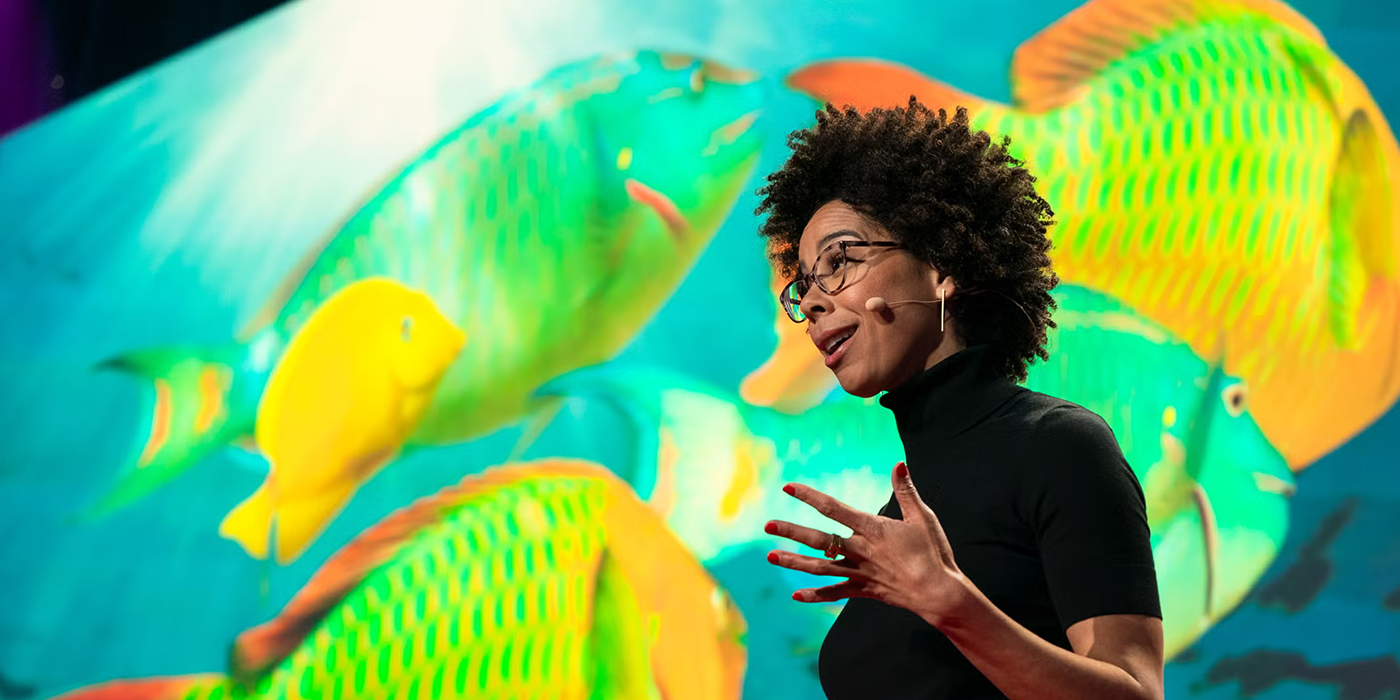Dr. Ayana Elizabeth Johnson giving a presentation in front of a photo of fish